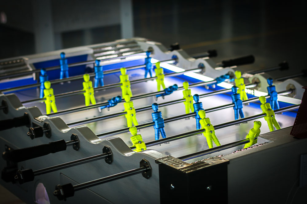 Futbolín modelo Tsunami iluminado con luces LED azules y blancas, con jugadores de color amarillo y azul, disponible para alquiler y explotación por parte de una empresa en Estepa.